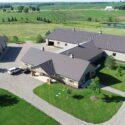 Aerial view of front of equestrian building with large garage to the left.