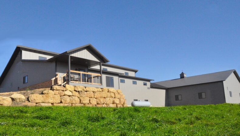 Bottom up angle of the post-frame home with beige siding.