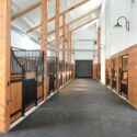 Interior of barn with several horse stalls on left side.