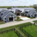 Front of equestrian building with white siding and gray roofs.
