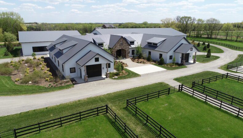 Front of equestrian building with white siding and gray roofs.