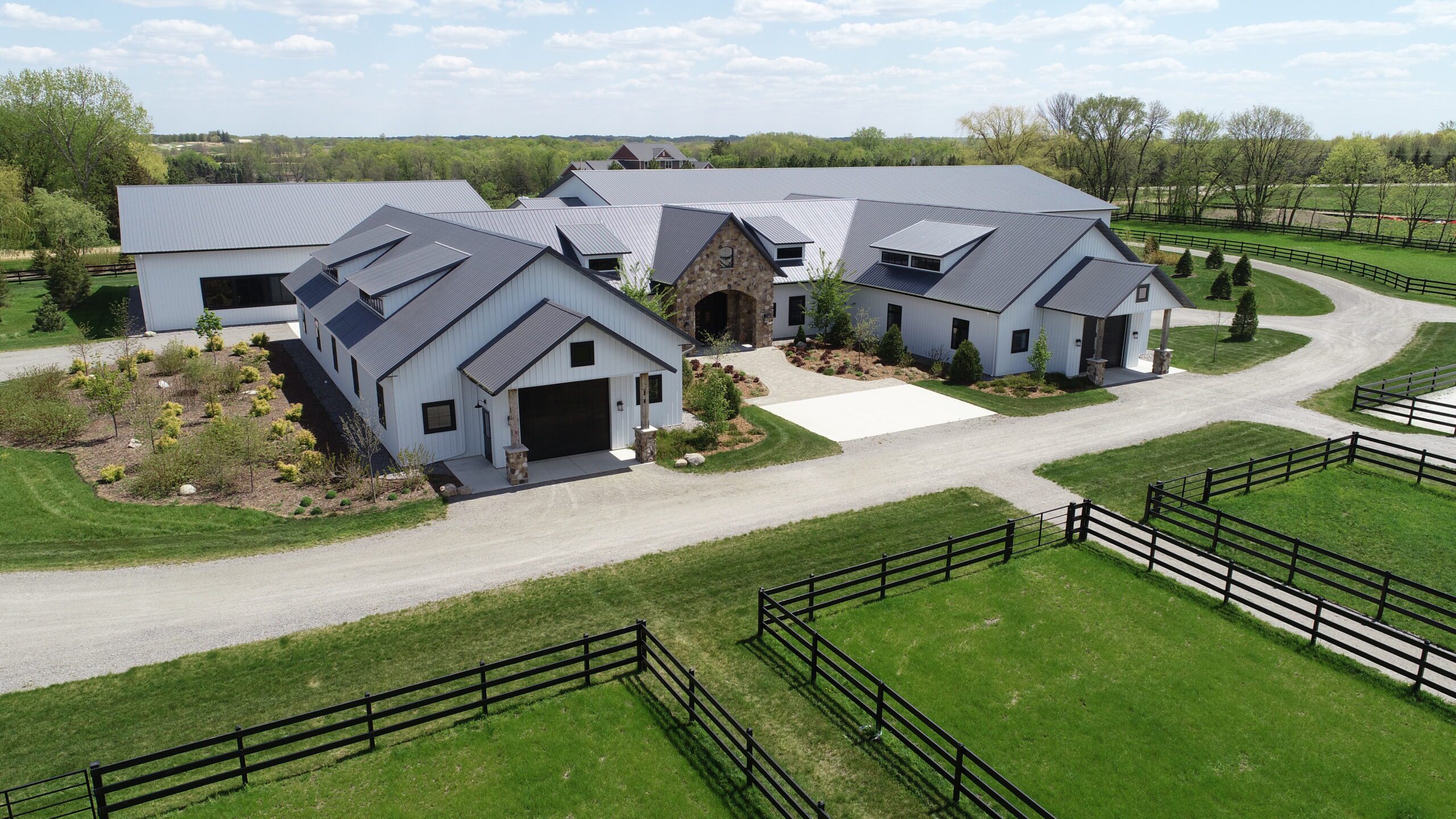 Front of equestrian building with white siding and gray roofs.