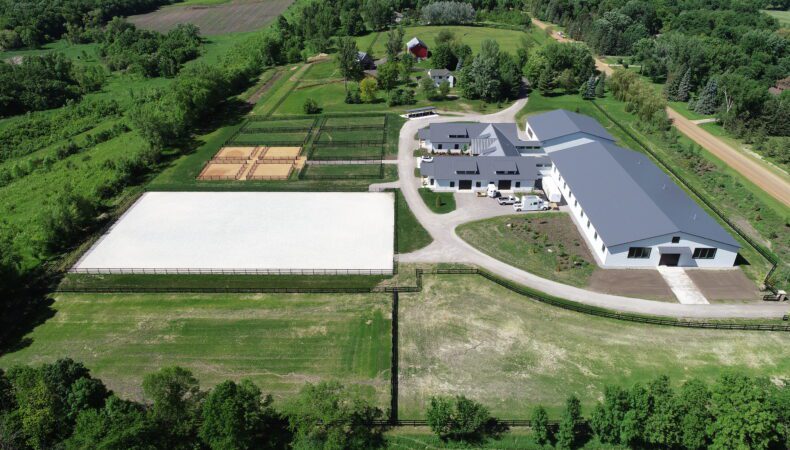 Drone view with large fields on left and buildings on right.