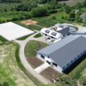 Drone view of property showing large equestrian facility on right.