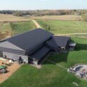 Drone view of whole home from large garage/storage area with stone firepit on right