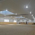 Indoor riding space with bright windows and garage door.
