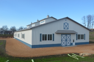 Front of equestrian building - white siding with blue elements.