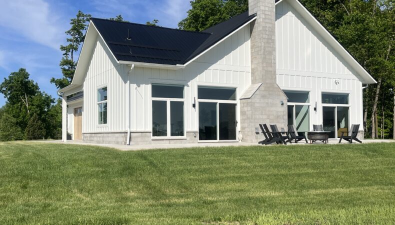 Exterior side view of home with large chimney and patio.