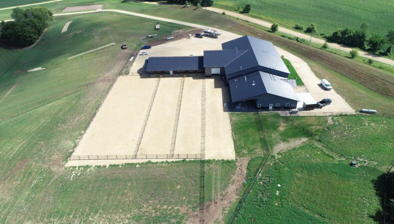 Drone view of left side of property with large fenced area.