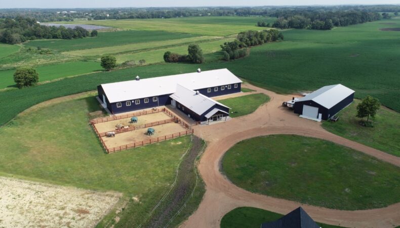 Aerial view of full property with one large equestrian facility and smaller building.