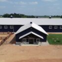 Front of equestrian building with fenced area to the left.
