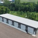 Aerial view of large, 6 garage door building, showing more of light gray roof