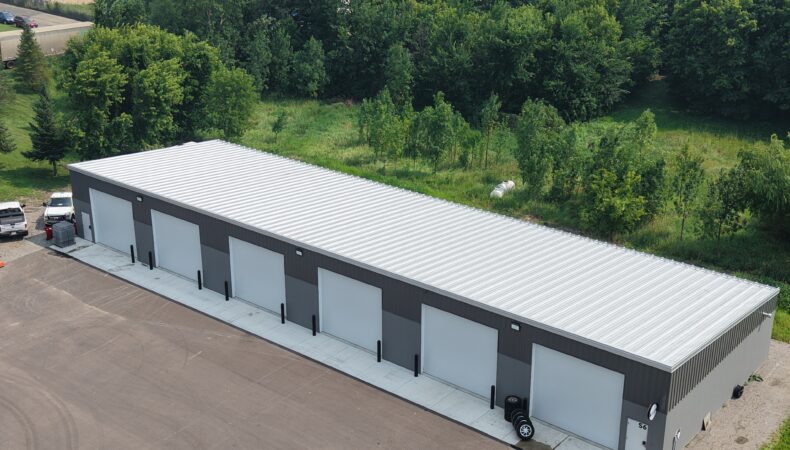 Aerial view of large, 6 garage door building, showing more of light gray roof