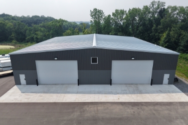 Front of gray building with 2 large white garage on right and left sides.