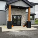 Front entrance of building with wood pillars and stone around doors.