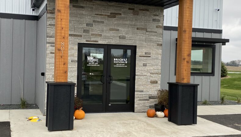 Front entrance of building with wood pillars and stone around doors.
