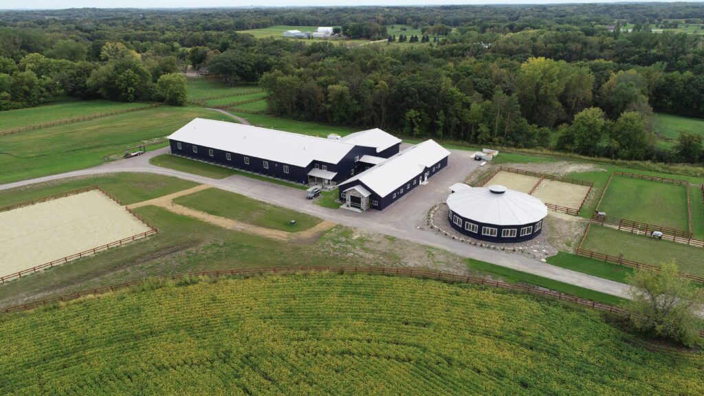 Aerial view of equestrian facility with barn and round riding stable.