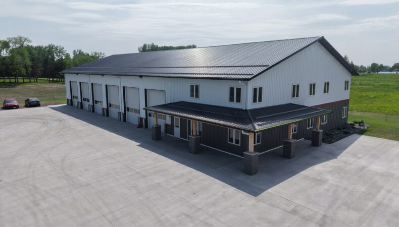 View of full building with entrance on right, garage space on left, parking lot in foreground