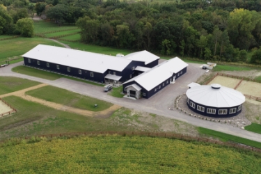 Aerial view of equestrian property with large barn and round riding stable.