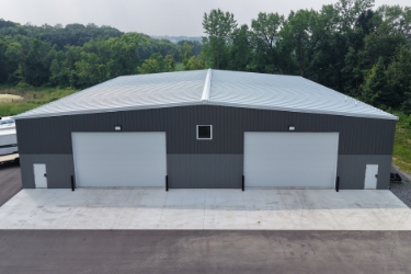 Gray PEMB building with large garage doors on right and left sides.
