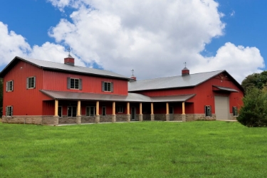 Large post-frame home with red siding and large front wraparound patio.