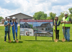 Staff standing by RAM General Contracting banner for start of project.